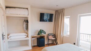 Un dormitorio con literas, un escritorio, una silla, un televisor y una ventana.