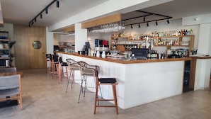 Zona de bar moderna con una barra central, taburetes y una variedad de botellas y vasos.