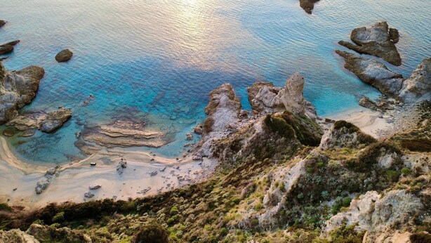 A coastal landscape with rocky formations and clear blue waters. - Kitty House (Spilinga)
