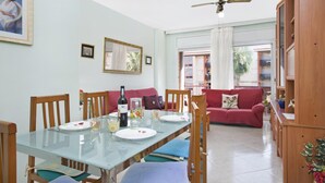 Un comedor con una mesa de vidrio, sillas de madera y un sofá rojo al fondo.