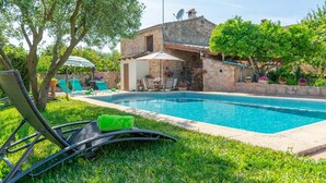 A swimming pool with lounge chairs and a stone building in the background. - Can Fiolet in Algaida (Algaida)
