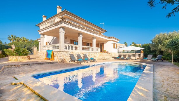 Ein zweistöckiges Haus mit Swimmingpool, Sitzgelegenheiten im Freien und einer Stein-Fassade.