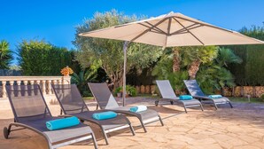 Eine Terrasse mit Liegestühlen und einem großen Sonnenschirm.