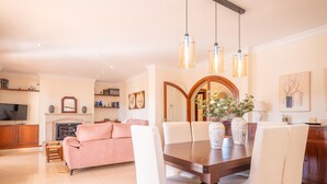 Ein modernes Wohnzimmer mit Esstisch, Stühlen, Kamin und Fernseher.