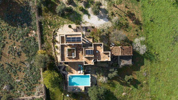 Et luftfoto af et moderne hus med swimmingpool, flere værelser og en patio.