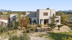 Et moderne hus med en patio, omgivet af ørkenvegetation og bjerge i baggrunden.