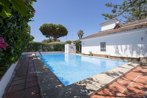 A swimming pool with a tiled deck, surrounded by white walls and greenery. - Fuente Alegre in Chiclana de la Frontera (Chiclana de la Frontera)