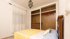 A bedroom with a bed, a wardrobe, and a hanging rack with clothes.