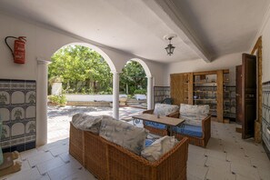 A spacious patio area with wicker furniture, a tiled floor, and a view of greenery through arches. - Fuente Alegre in Chiclana de la Frontera (Chiclana de la Frontera)
