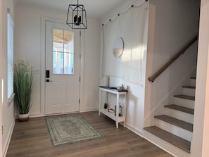 Staircase leads to an upper level, flanked by a console table and a potted plant.