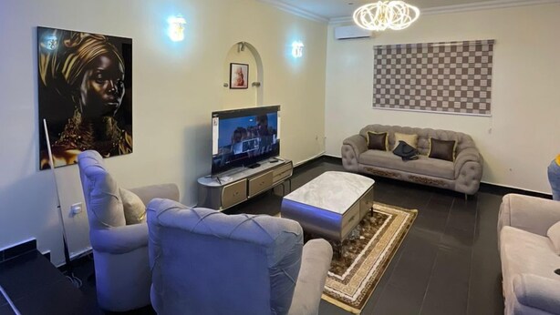 A modern living room with a flat-screen TV, two sofas, a coffee table, and a chandelier. - Trans Amadi Gardens Duplex (Port Harcourt)