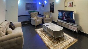 A modern living room with a pool table, comfortable seating, a flat-screen TV, and a decorative chandelier. - Trans Amadi Gardens Duplex (Port Harcourt)