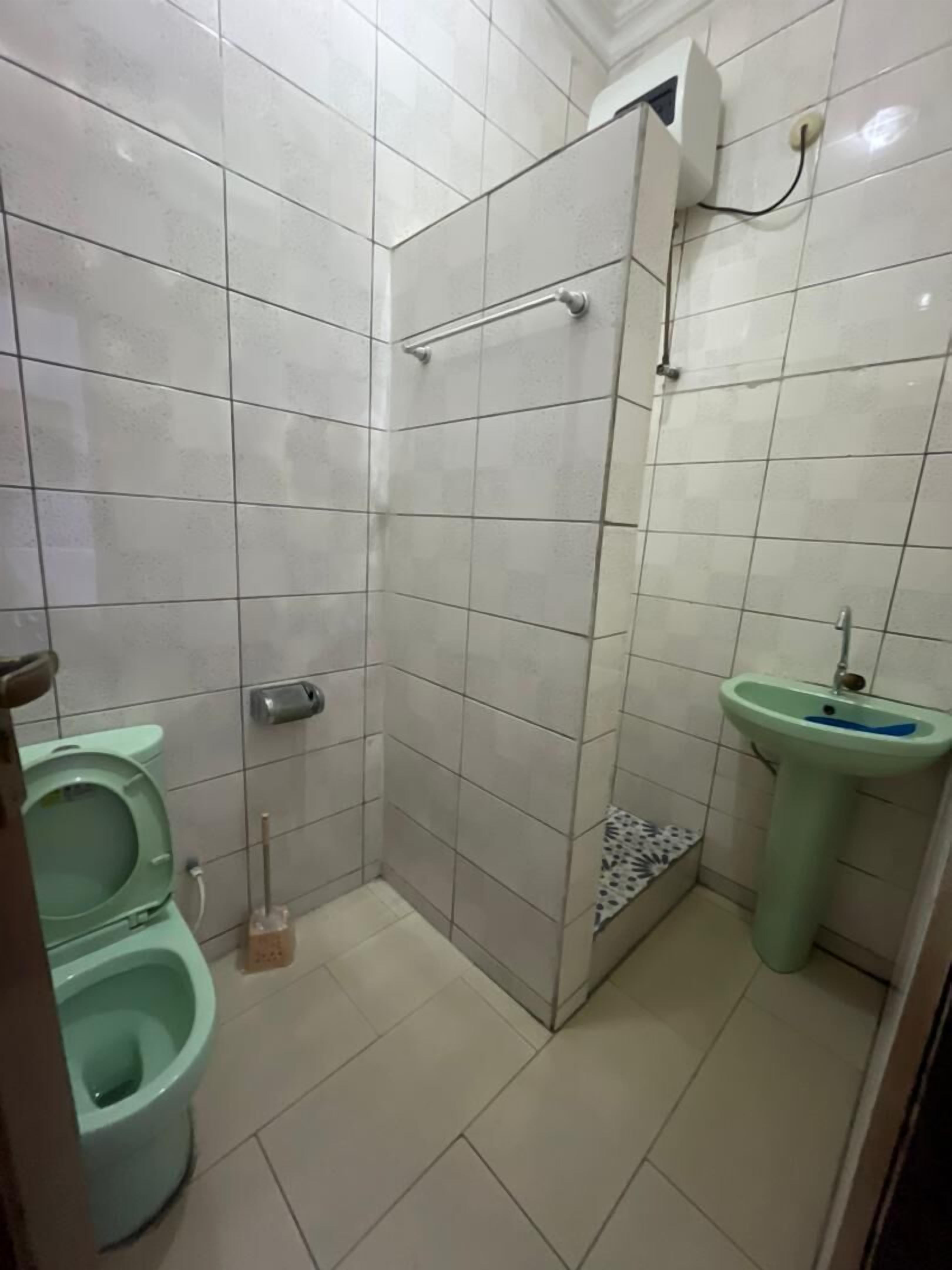 Et lille badeværelse med fliser, toilet, bidet og håndvask.