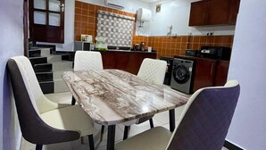 A modern kitchen with a marble table and chairs, a built-in oven, and a coffee machine. - Trans Amadi Gardens Duplex (Port Harcourt)