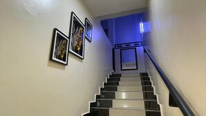A staircase with alternating black and white steps, a light fixture at the top, and three framed pictures on the wall. - Trans Amadi Gardens Duplex (Port Harcourt)