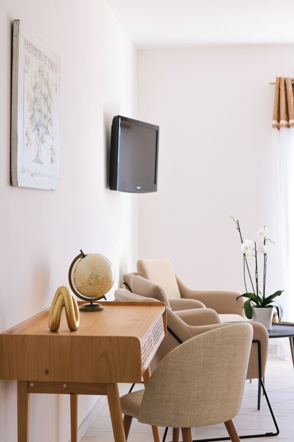 Una sala moderna con un escritorio de madera, un globo terráqueo, un televisor montado en la pared y un sofá color beige.
