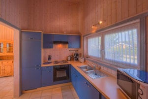 Cozinha compacta com armários de madeira, fogão, micro-ondas e uma janela grande que proporciona iluminação natural.