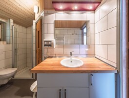 A modern bathroom with a wooden vanity, a sink, and a mirror.