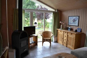 Una sala acogedora con chimenea, televisor, una silla de mimbre y un mueble de madera.