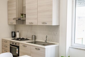 Een koelkast, een oven, een kookplaat, kookgerei, borden en bestek