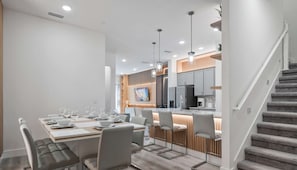 Une cuisine moderne avec des meubles gris, un îlot central et des luminaires suspendus.