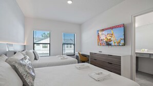 Une chambre d’hôtel avec deux lits, un bureau, une chaise, une télévision et une salle de bain.