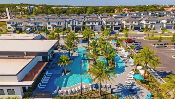 Uma área residencial com casas modernas, piscina e palmeiras.