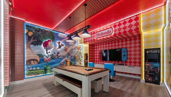 Une chambre sur le thème de Nintendo, avec une table de billard, un téléviseur et des consoles de jeux.