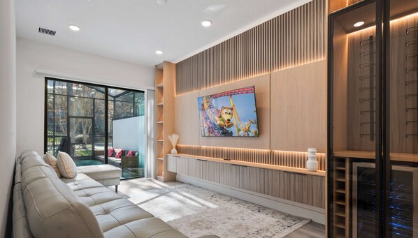 A modern living room with a large sofa, a glass door leading to a balcony, and a wall-mounted TV. - The Epic 10406 Paradiso Grande Resort Orlando Florida (Orlando)