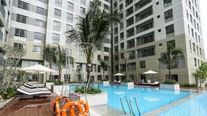 Ein moderner Poolbereich eines Hotels mit klarem, blauem Wasser, Holzterrasse und Liegestühlen.