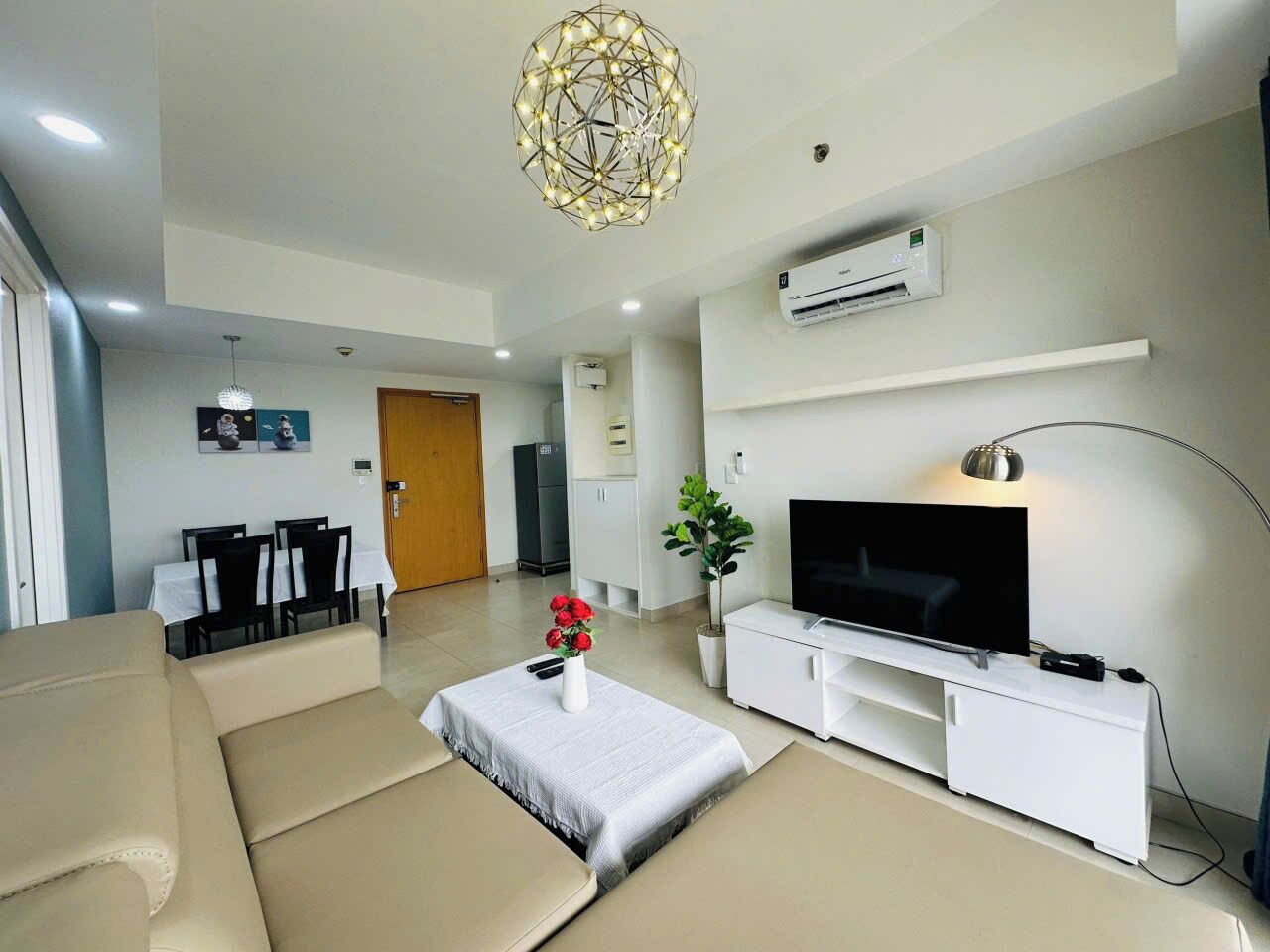 A modern living room with a sofa, a TV, and a dining area with chairs and a table.