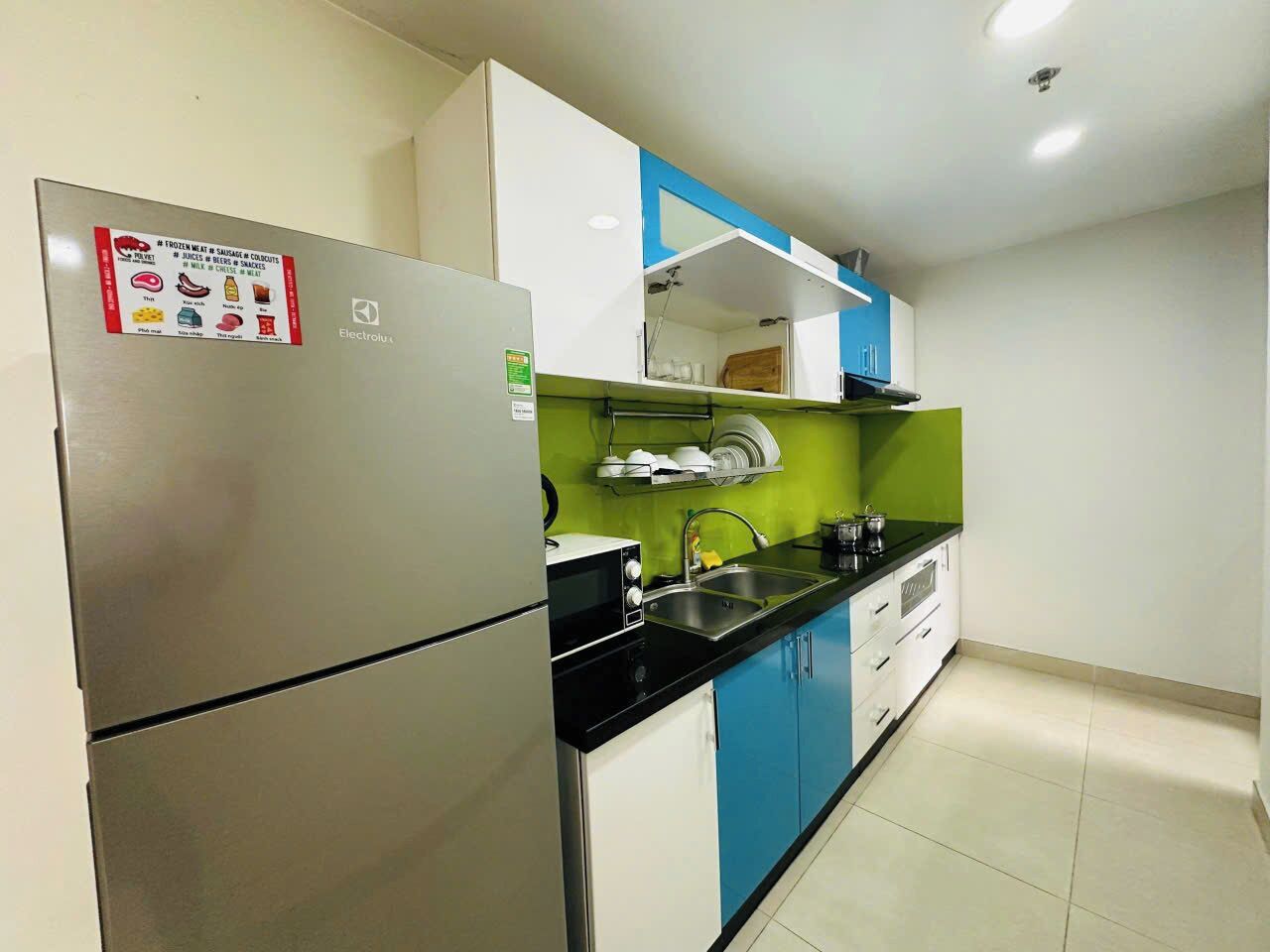 Cucina con frigorifero in acciaio inossidabile, forno a microonde, lavello e pensili.