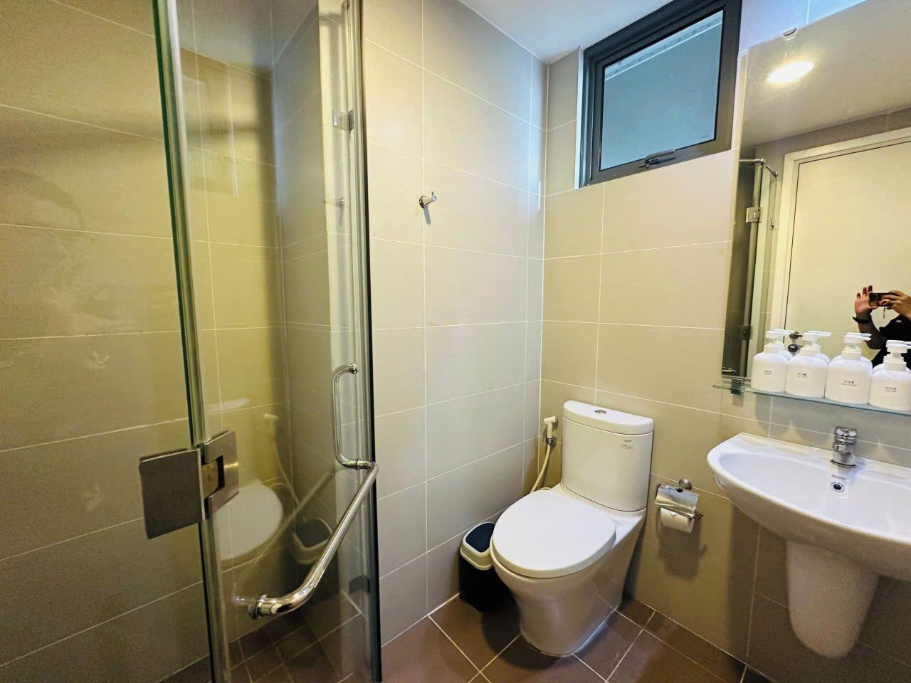 A bathroom with a glass-enclosed shower, a toilet, and a sink.
