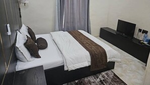 Une chambre d’hôtel moderne équipée d’un lit, d’une télévision et d’un bureau.