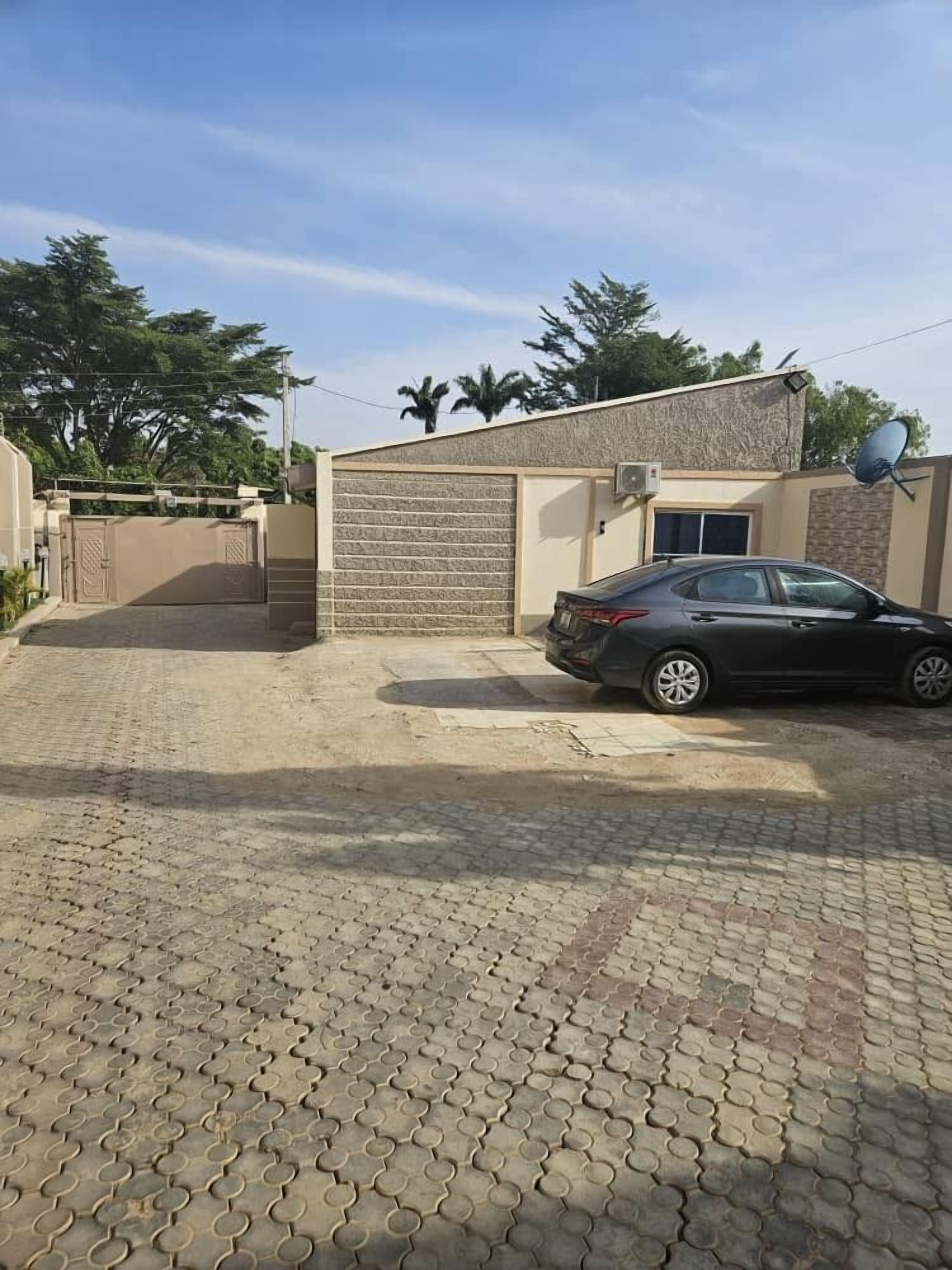 A paved driveway leading to a gated entrance with a car parked nearby.