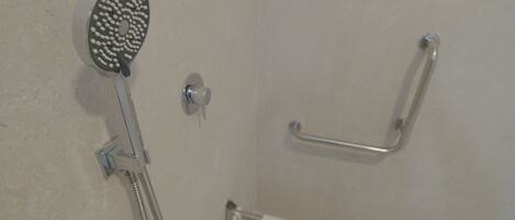 A shower with a handheld showerhead and a grab bar.