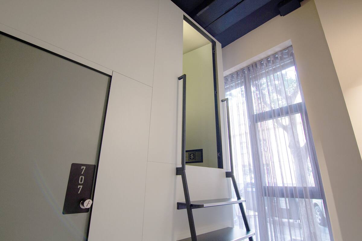 A room with a door marked '707', a window with sheer curtains, and a visible staircase.