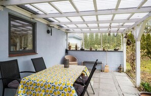 A covered patio with a table and chairs, a window with a view of trees, and outdoor lighting. - Lovely home in Grevinge with WiFi (Grevinge)