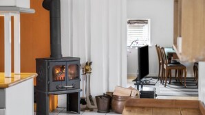 A living room with a wood-burning stove, a television, and a dining area with wooden chairs. - Lovely home in Grevinge with WiFi (Grevinge)