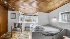 A compact bedroom with a sloped ceiling, a single bed, a chair, a radiator, and a window with a view of trees. - Lovely home in Grevinge with WiFi (Grevinge)