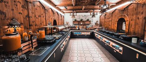 Une cuisine spacieuse dotée d’un îlot central, de murs en bois et d’un revêtement de sol en carrelage hexagonal.