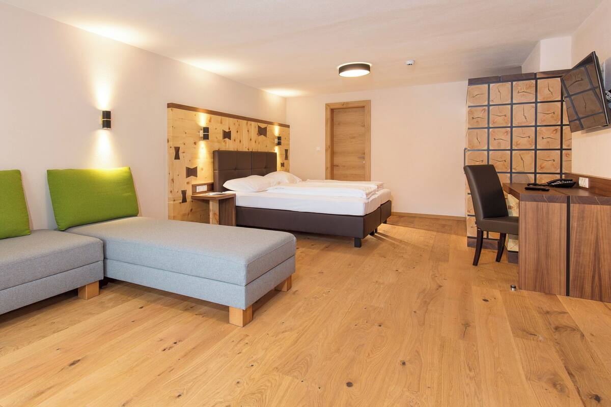A modern hotel room with a bed, a sofa, a desk, and a chair.