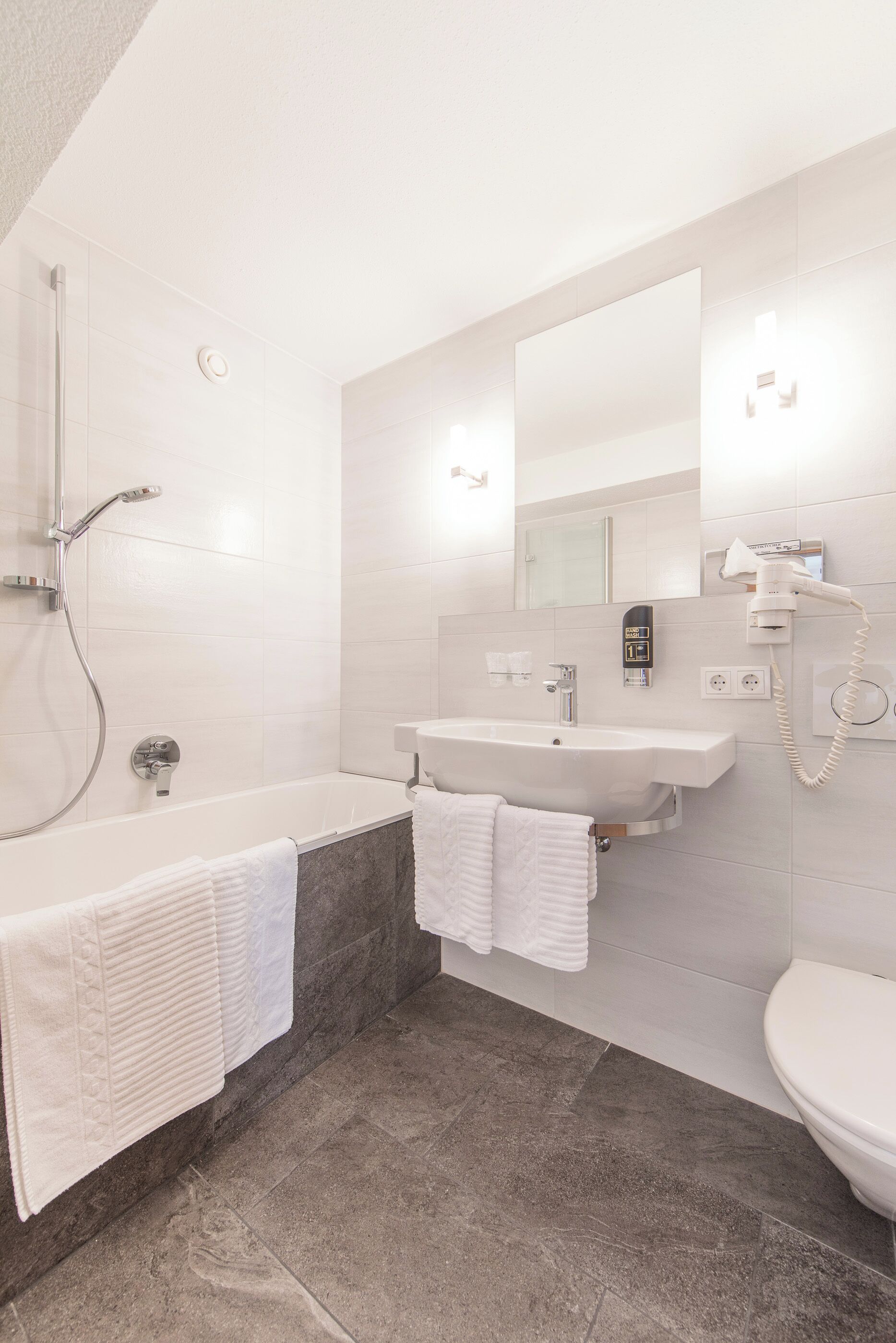 A modern bathroom with a bathtub, a sink, and a toilet.