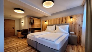 A modern hotel room with a large bed, wooden panel walls, and built-in lighting. - Hotel Birkenhof (Soelden)