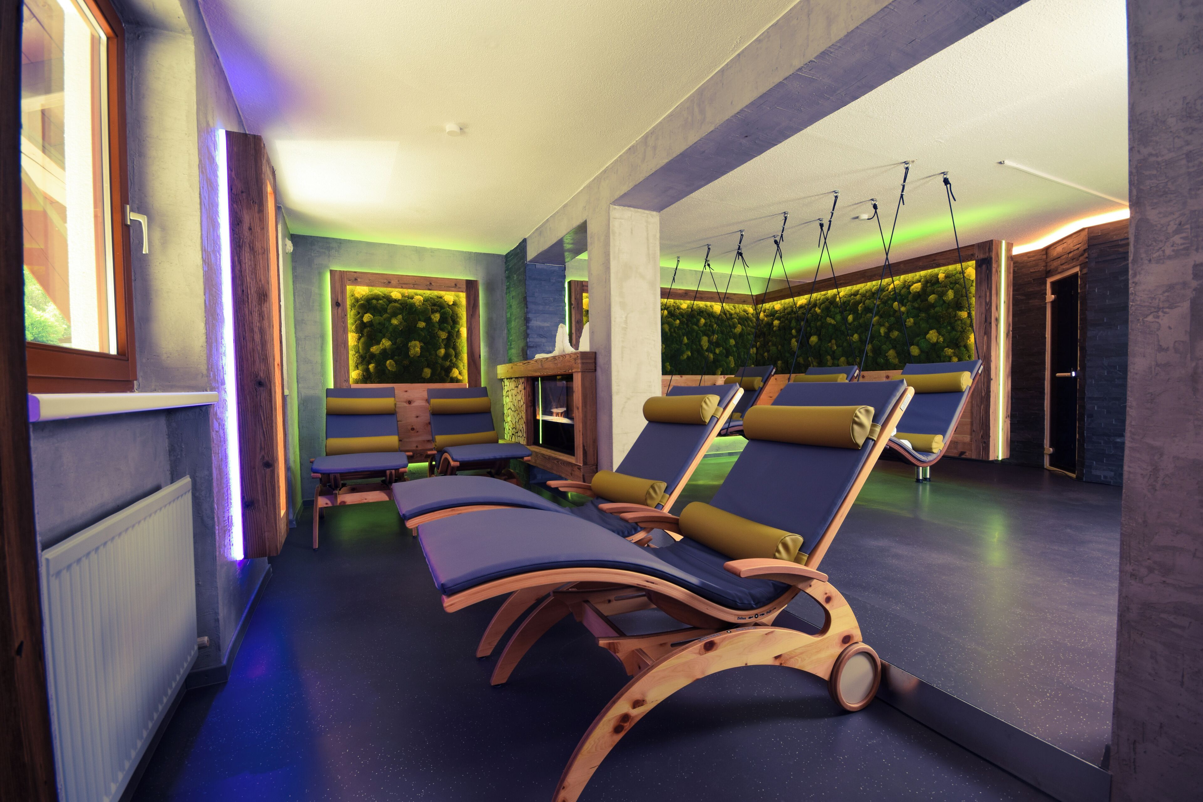 A spa area with wooden loungers, a green wall with plants, and a ceiling with hanging lights.