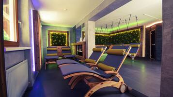 Een wellnessruimte met houten ligbedden, een groene wand met planten en een plafond met hangende lampen.