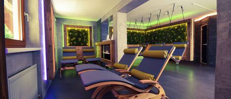 A spa area with wooden loungers, a green wall with plants, and a ceiling with hanging lights.