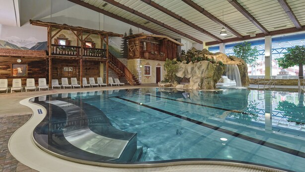 An indoor swimming pool with a wooden cabin and waterfall feature. - Hotel Birkenhof (Soelden)