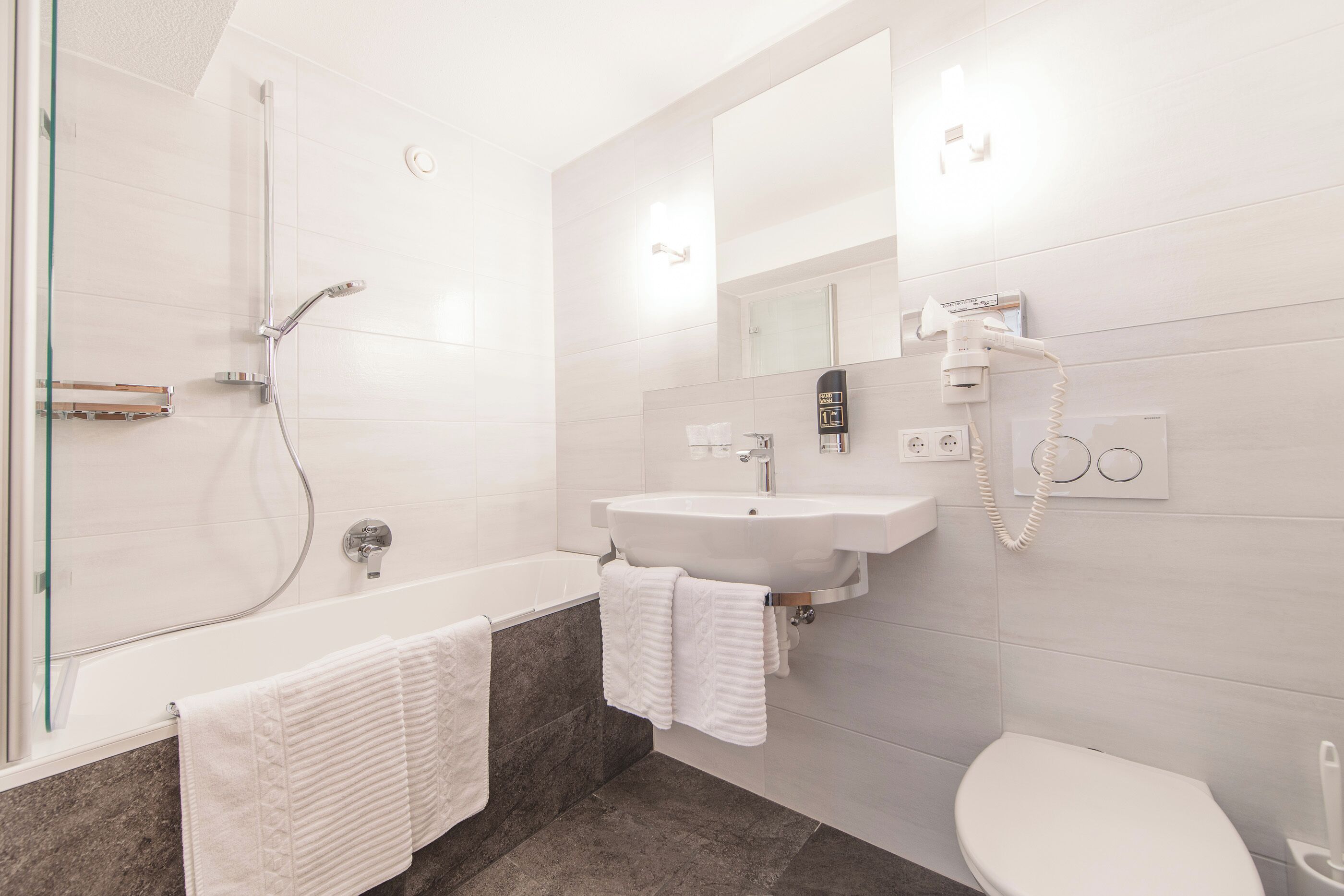 A modern bathroom with a glass-enclosed shower, a white sink, and a toilet.