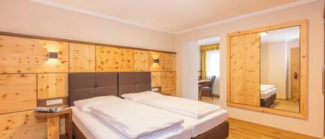 Un dormitorio con cabecera de madera, un espejo grande y una mesita de noche con lámpara.